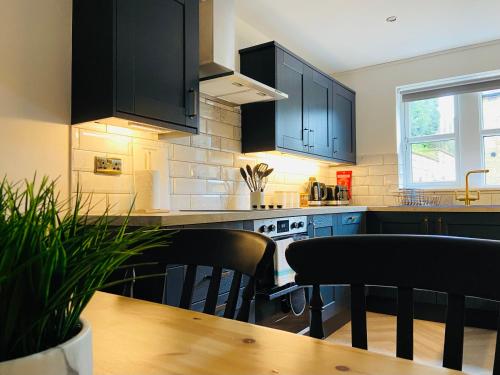 a kitchen with black cabinets and a wooden table at Royal Calderdale Lodge in Halifax