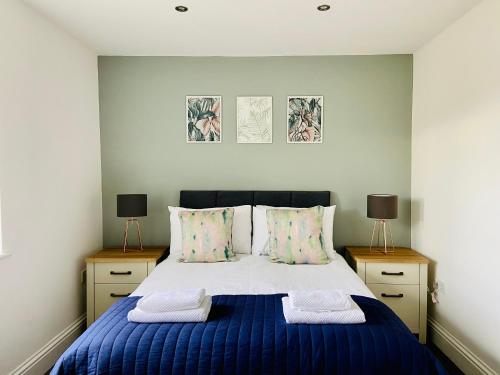 a bedroom with a blue bed with two night stands at Royal Calderdale Lodge in Halifax