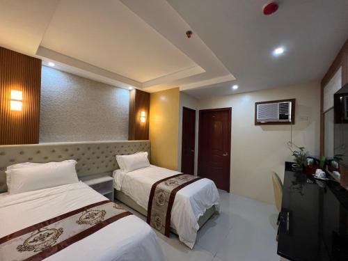 een hotelkamer met 2 bedden en een televisie bij Hotel Erich in Tuguegarao City