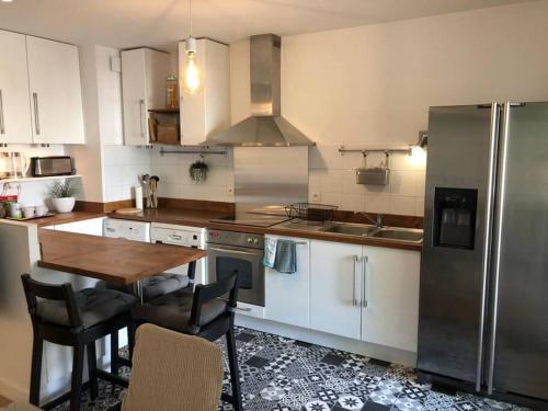 une cuisine avec une table et un réfrigérateur en acier inoxydable dans l'établissement 60 Sweet Home au cœur de Marseille pres du Tramway, à Marseille