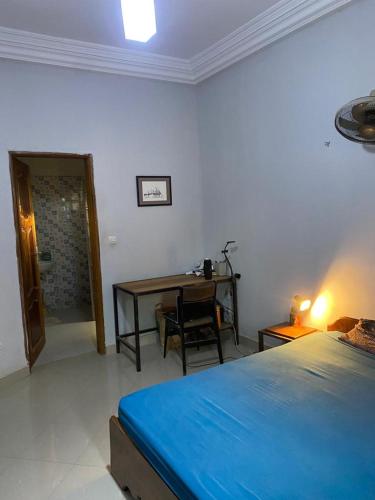 een slaapkamer met een bed, een bureau en een tafel bij CHAMBRE DHOTE SILLA in Mbour