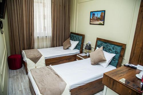 Habitación de hotel con 2 camas y escritorio en Hayat Samarkand en Samarcanda