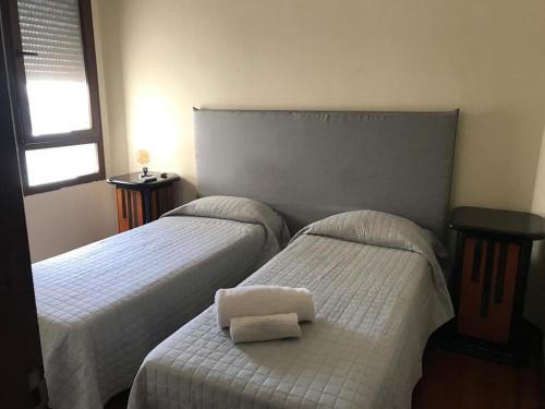 two beds in a bedroom with two white sheets at The Wall Montevideo [203] Vive en la Ciudad Vieja in Montevideo