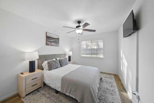 een witte slaapkamer met een bed en een plafondventilator bij IAH Place: 4 bed, patio-sleeps 8+ in Humble