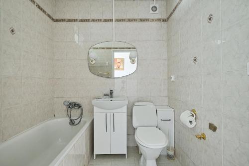 uma casa de banho com um WC, uma banheira e um espelho. em Noctis City Center em Varsóvia