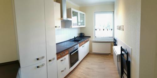 uma cozinha com armários brancos, um lavatório e uma janela em Ferienhaus Hahn em Bad Frankenhausen