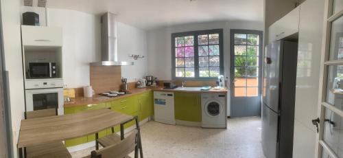 une cuisine avec des armoires jaunes et vertes et une table dans l'établissement Villa la Bergerie, à Bormes-les-Mimosas