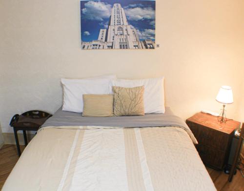 a bed with two pillows and a picture on the wall at Comfortable Apartment - Pittsburgh's Little Italy in Pittsburgh