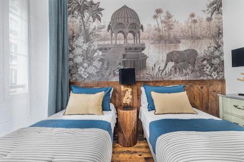 - 2 lits dans une chambre avec une fresque murale dans l'établissement Orient Express, à Paris