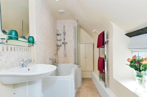 uma casa de banho branca com um lavatório e uma banheira e um lavatório. em Cidermill Cottage em Chipping Campden