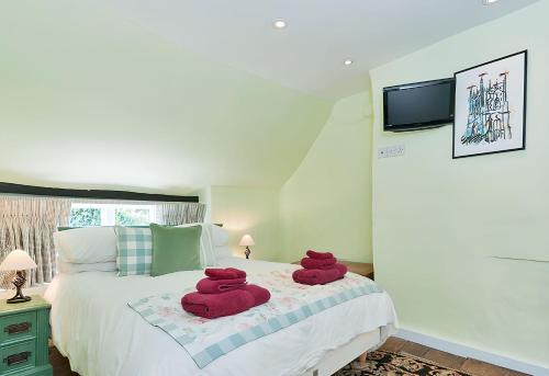 a bedroom with two red towels on a bed at Cidermill Cottage in Chipping Campden