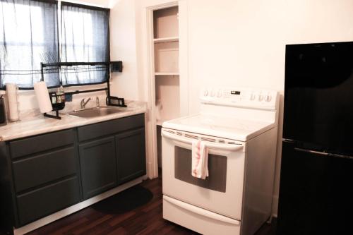 uma cozinha com um fogão branco e um lavatório em Comfy and Spacious 3 BR - Easy City Access em Pittsburgh