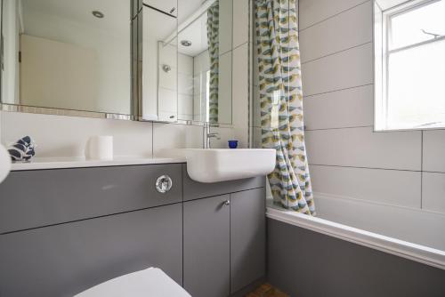 ein weißes Badezimmer mit Waschbecken und Spiegel in der Unterkunft Whiteleaf Cottage in Lyme Regis