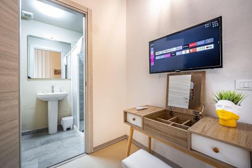 uma casa de banho com um lavatório e uma televisão na parede em la loggia del porcellino em Florença