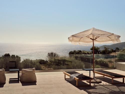 un patio con sombrilla, mesa y sillas en Elle Lux Villa, Essence of Endless Blue, By ThinkVilla, en Agios Nikolaos