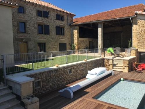 une cour arrière avec une piscine et un bâtiment dans l'établissement GITE La Maison de Paul et Margaux, à Châteauneuf-de-Galaure