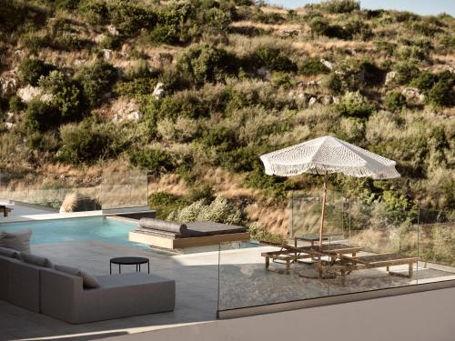 a pool with a couch and a table and an umbrella at Elle Lux Villa, Essence of Endless Blue, By ThinkVilla in Agios Nikolaos