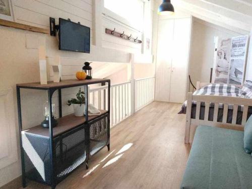 a living room with a bed and a television on a wall at La petite Maison d'Enveitg in Enveitg