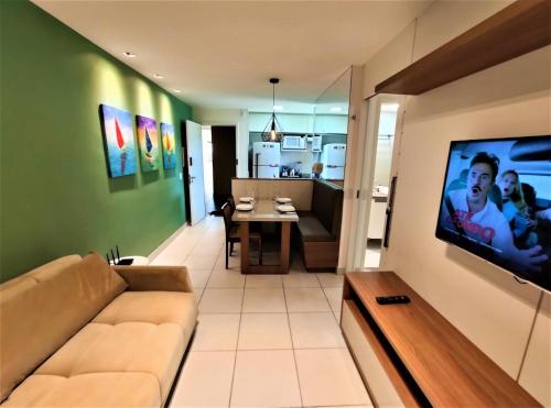 a living room with a couch and a tv on a wall at VG Sun Cumbuco Sea Breeze Vista Mar in Cumbuco