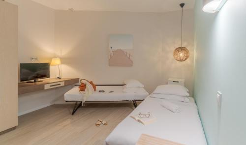 a small room with two beds and a tv at Pestana Alvor Praia Premium Beach & Golf Resort in Alvor
