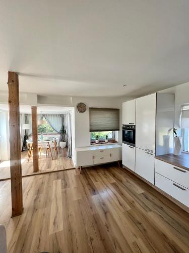 a large kitchen with white cabinets and a dining room at ReinuHome in Viljandi
