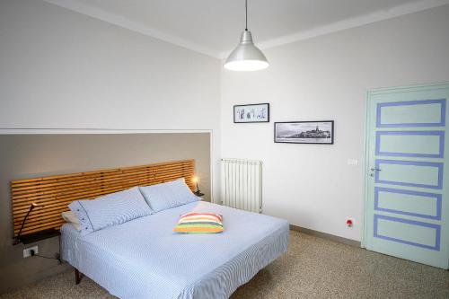 a bedroom with a white bed with a wooden headboard at Casa stella in San Lorenzo al Mare