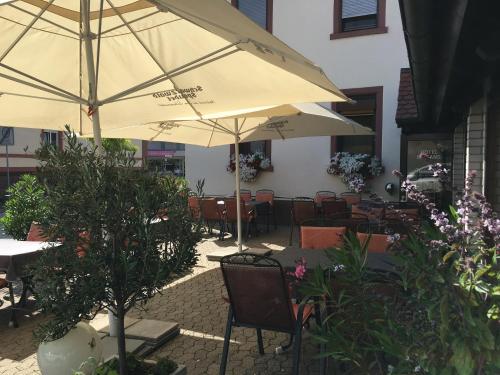 d'une terrasse avec des tables, des chaises et un parasol. dans l'établissement Hotel Alessandro, à Neuried