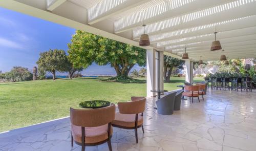 a patio with chairs and tables and a view of a park at Pestana Alvor Praia Premium Beach & Golf Resort in Alvor