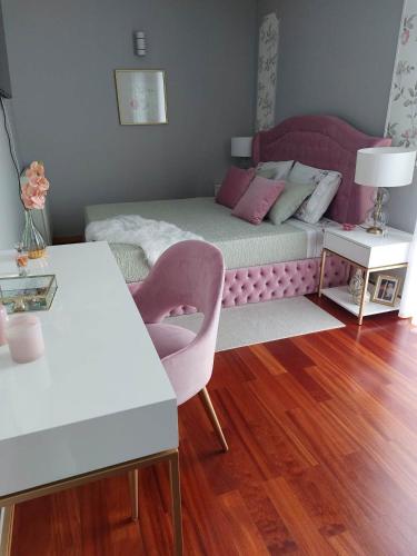 sypialnia z łóżkiem i różowym krzesłem w obiekcie Appartement en face de la mer w mieście Azurara