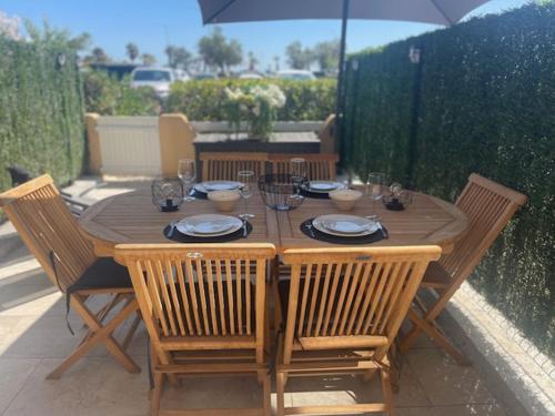 une table en bois avec quatre chaises et un parasol dans l'établissement La Martina, à Sainte-Maxime