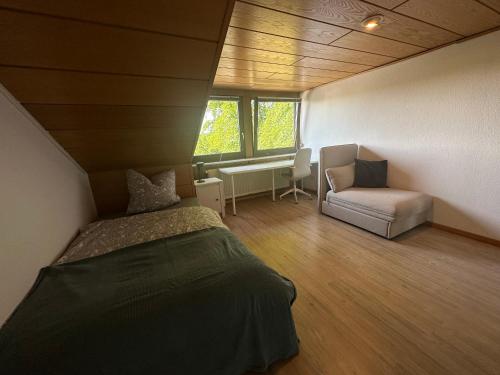 een slaapkamer met een bed, een stoel en een bureau bij In der Natur gelegene Wohnung mit Weitblick in Hüthum