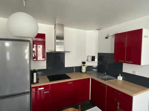 a kitchen with red cabinets and a stainless steel refrigerator at Belle maison de ville rénovée in Lavardac