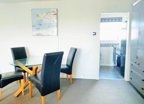 a dining room with a table and black chairs at Dune Roamin': Sea Palling's Treasure - NOW with TV in Norwich