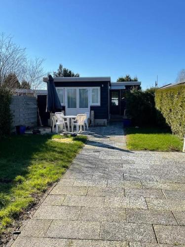 a patio with a table and an umbrella and a house at Mooie chalet met grote tuin dichtbij Amsterdam in Opmeer