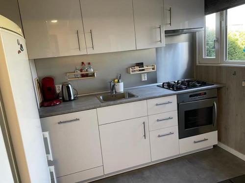 a kitchen with white cabinets and a stove top oven at Mooie chalet met grote tuin dichtbij Amsterdam in Opmeer