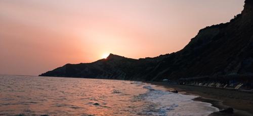 a sunset on the beach with a mountain in the background at Hermes in Kavos