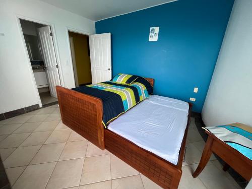 a small bedroom with a bed and a blue wall at Exclusivo departamento frente al mar en Same, Casa Blanca in Same