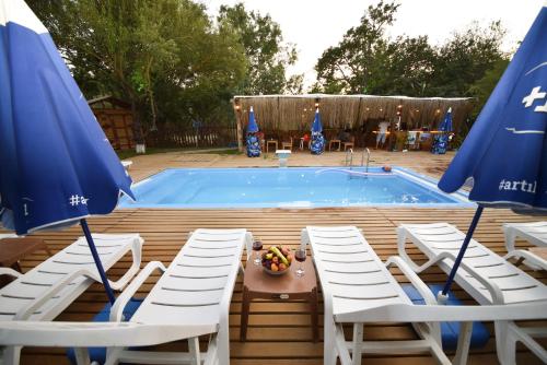a pool with chairs and a table and umbrellas at BADEM AĞACI BUGALOWLARI in Kas
