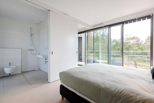 1 dormitorio con 1 cama grande y baño en Dune Villa 7 en Zandvoort