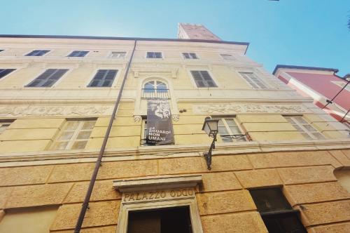 a tall yellow building with a sign on it at Palazzo Oddo Rental Rooms in Albenga