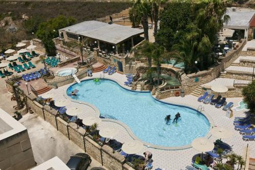 a swimming pool with several tables and chairs at Porto Azzurro Aparthotel in St. Paul's Bay