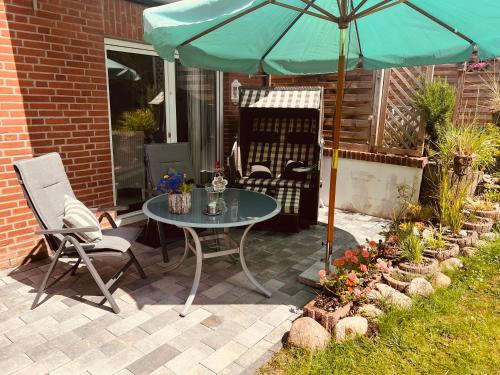 un patio con mesa, sillas y sombrilla en SOLund - Sonne im Herzen - ruhige und sonnige Ferienwohnung mit Terrasse und Garten nahe Strand und Ostsee en Schönhagen