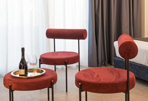 due sedie rosse con una bottiglia di vino e un bicchiere di Spazio Gagarin Residence a Matera