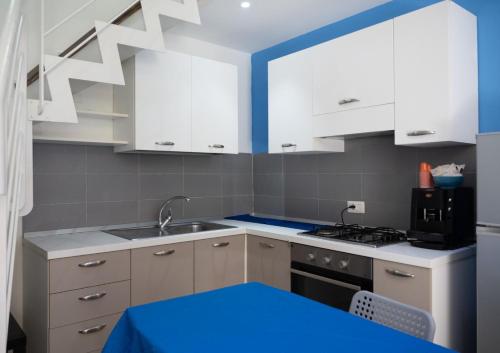 cocina con armarios blancos y pintura azul en las paredes en Carpeviam - Guesthouse, en Benevento