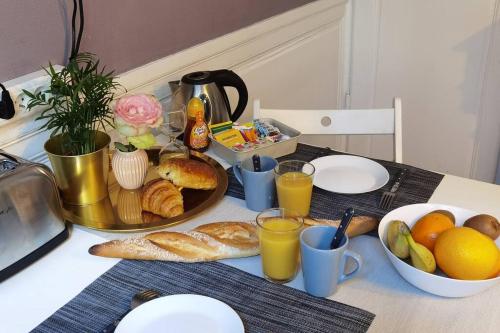 una mesa con desayuno de pan y zumo de naranja en Le 1675_I - Confort et charme de l'ancien, en Rouen