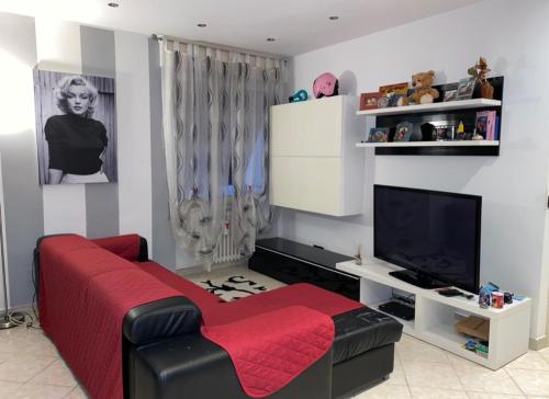 sala de estar con sofá rojo y TV en Home Chiara, en San Remo