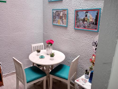 una mesa con sillas y un jarrón con flores. en Hotel Maceo 55 - Colonial Inn, en Bogotá
