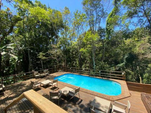 una piscina en una terraza de madera con sillas en Bombinhas Guest House, en Bombinhas