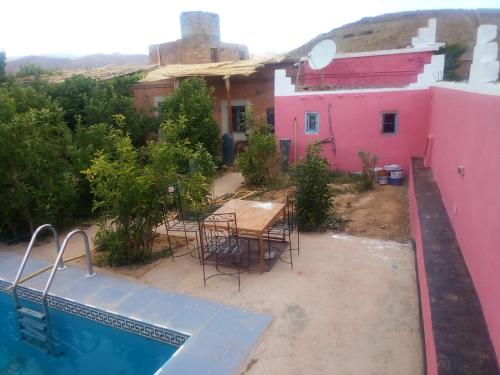 a house with a table and chairs and a swimming pool at Riad Bouchra in Tamtetoucht