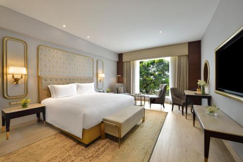 Schlafzimmer mit einem großen weißen Bett und einem Schreibtisch in der Unterkunft Taj Gandhinagar Resort and Spa in Gandhinagar